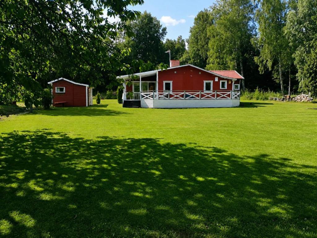 a red house in a grass field with a building at 5 person holiday home in MÖLLTORP-By Traum in Mölltorp