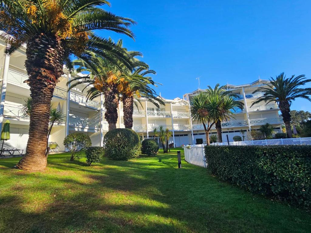 a large building with palm trees in front of it at Entre Foret et Ocean in Moliets-et-Maa