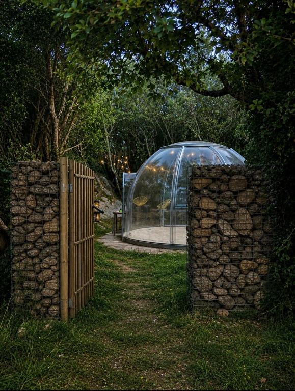 a glass house with a fence and a stone wall at Bulle d'Alma - Bio climatique in Sotta