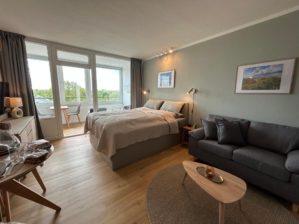 a bedroom with a bed and a living room with a couch at Apartment Nordly in Wendtorf