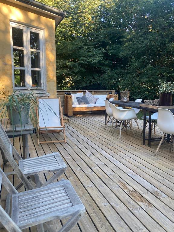 a wooden deck with chairs and a table and a couch at La Petite Ecole in Bindslev