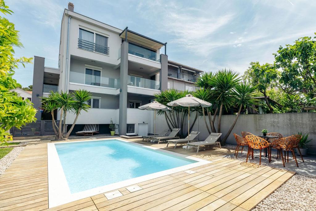 an image of a house with a swimming pool at Apartmani Pocco Locco in Biograd na Moru