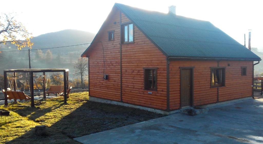 a small wooden house with a gambrel roof at Cottage Ozerniy in Lazeshchyna