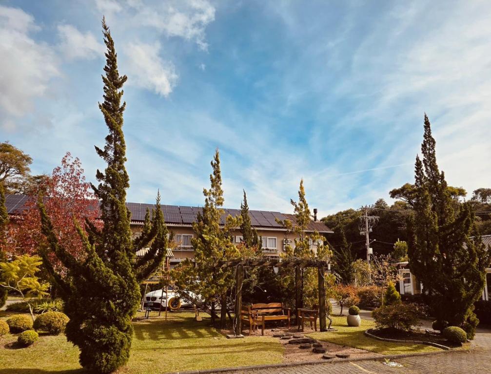a garden with trees and a house in the background at Pousada Quinta do Vale in Gramado