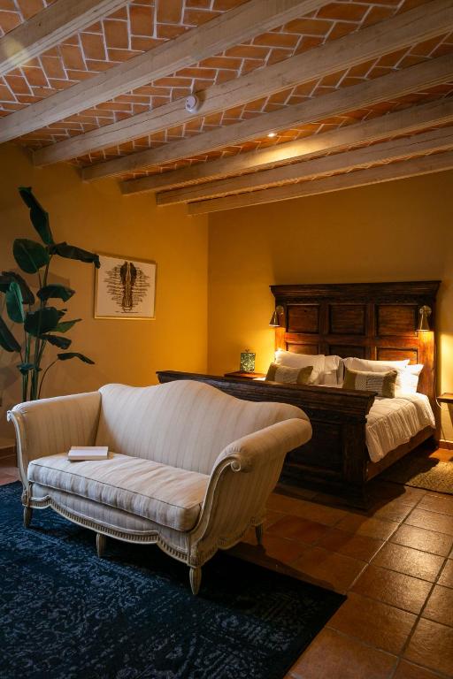 a bedroom with a bed and a couch in a room at Habibi Hotel and SPA in San Miguel de Allende