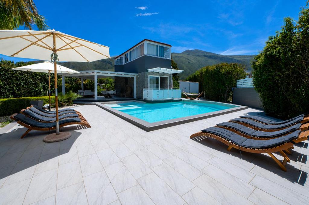 a swimming pool with two lounge chairs and an umbrella at Moresca Luxury Private Villa & Spa in Castellammare del Golfo