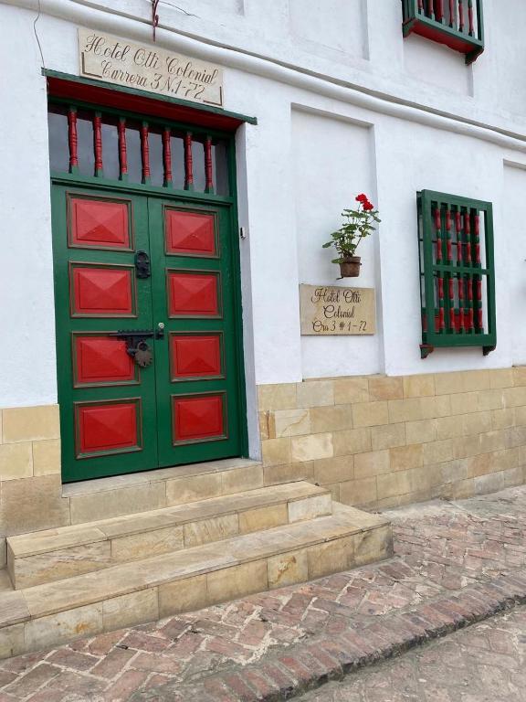 a green and red door on the side of a building at Hotel Otti Colonial in Monguí