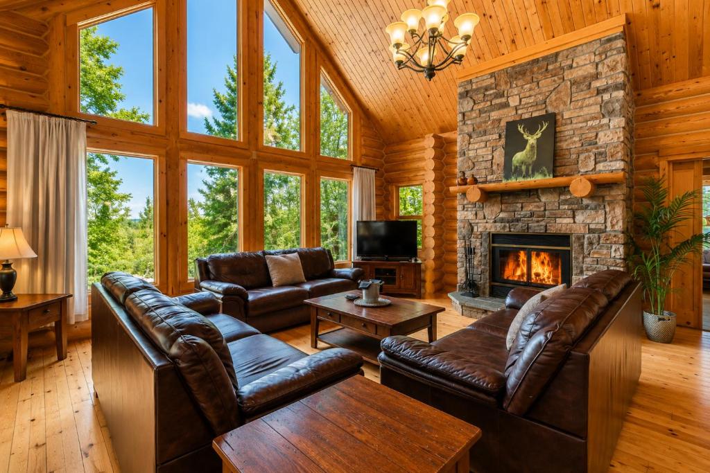 a living room with leather furniture and a stone fireplace at Fiddler Lake Resort - Deer 90 in Mille-Isles