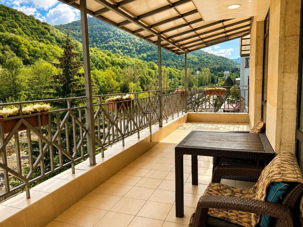 a balcony with a table and a view of the mountains at Riverside Penthouse in Dilijan in Dilijan