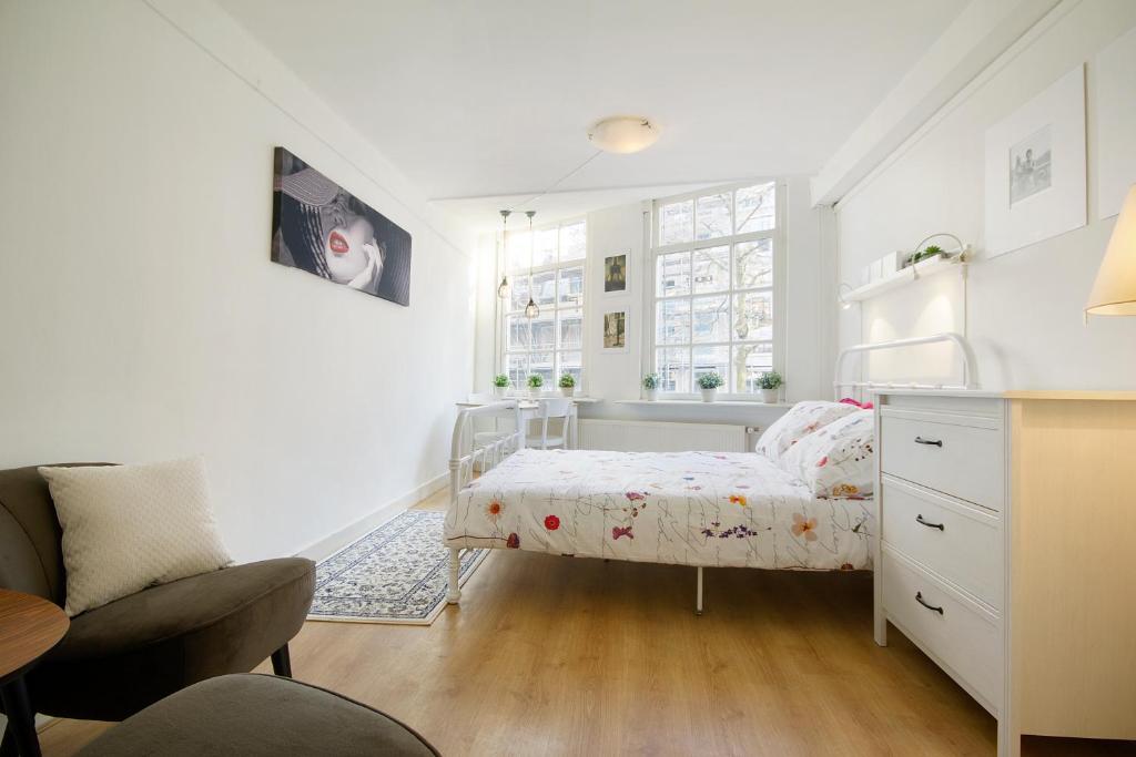 niewielka sypialnia z łóżkiem i krzesłem w obiekcie Spui's the Limit w Amsterdamie
