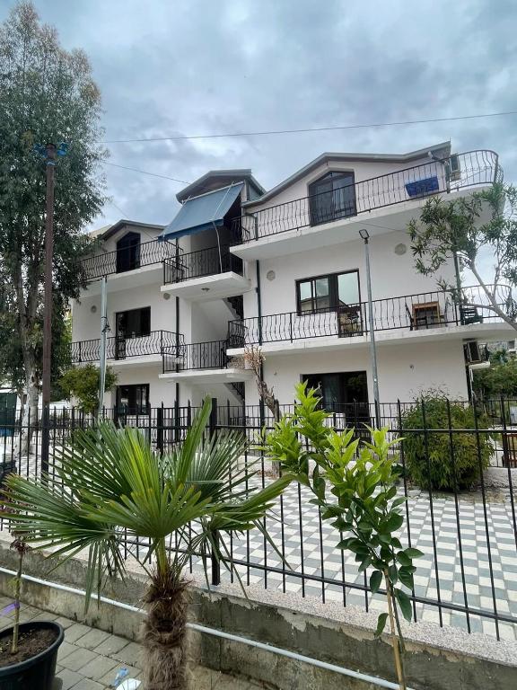 a white building with a fence in front of it at Hotel Gjinaj in Shëngjin