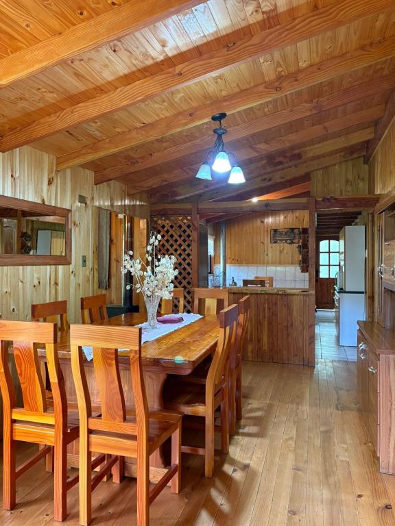 a kitchen and dining room with a wooden table and chairs at Parcela Peumayen casa 1 in Coñaripe