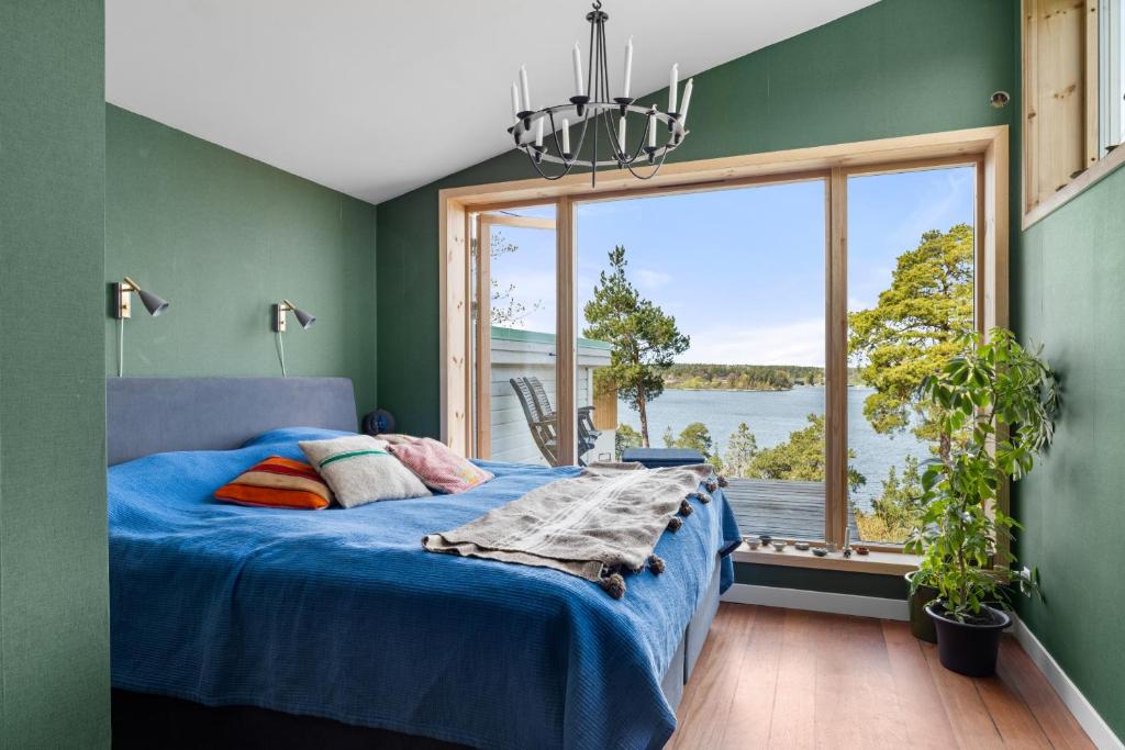 a bedroom with a blue bed and a large window at Cat-Friendly Archipelago Villa in Nacka