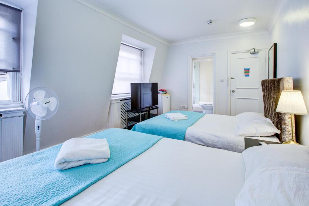 a hotel room with two beds and a fan at Boltons Residence Collection Hotel London in London