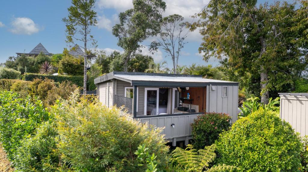 a tiny house in a garden with bushes at The Tawnys Gatehouse in Russell