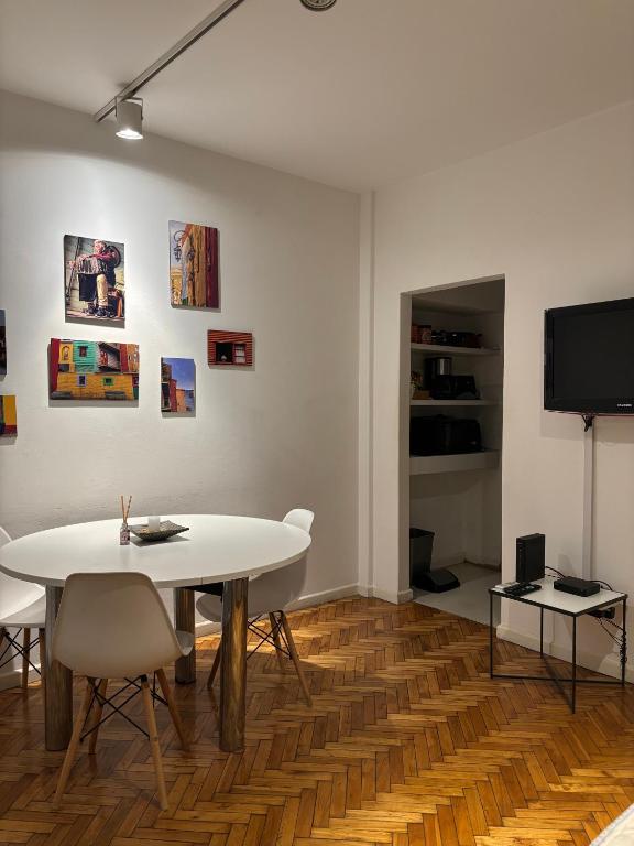 a dining room with a white table and a tv at RECOLETA APART in Buenos Aires