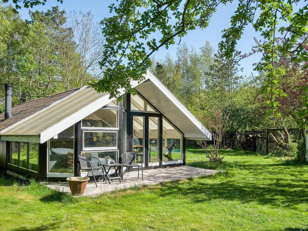 a glass house with a table and chairs in a field at 4 star holiday home in Gørlev in Gørlev