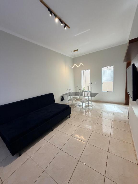 a living room with a black couch and a table at Casa Cambuí Molina in Franca