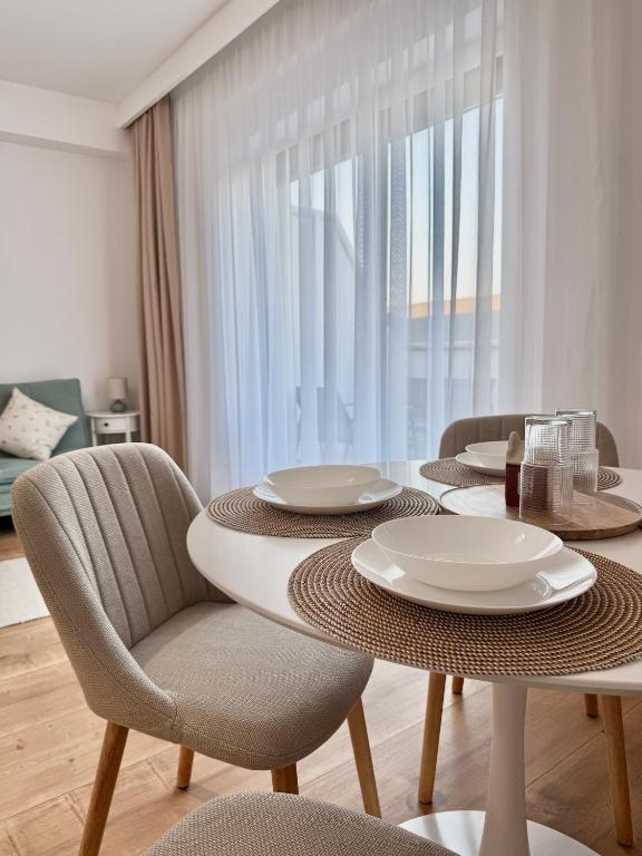 a dining room with a table with plates and chairs at Elegance Apartments in Baile Felix