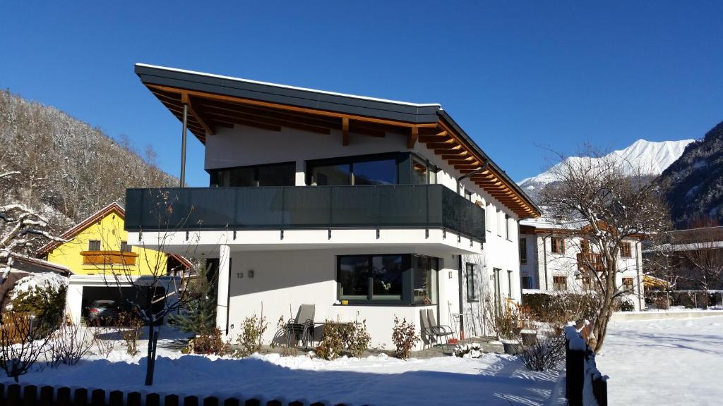 a house in the snow with mountains in the background at Apart Patscheider in Ried im Oberinntal