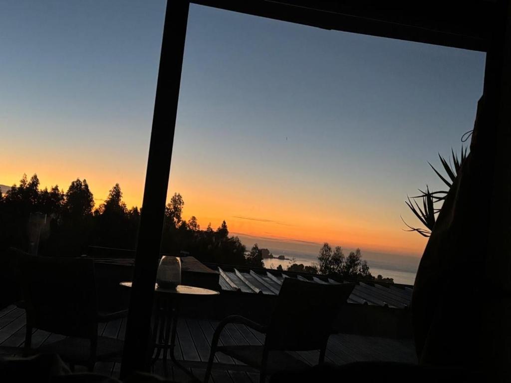 a sunset seen through a window of a patio at Paraisopingueral in Dichato