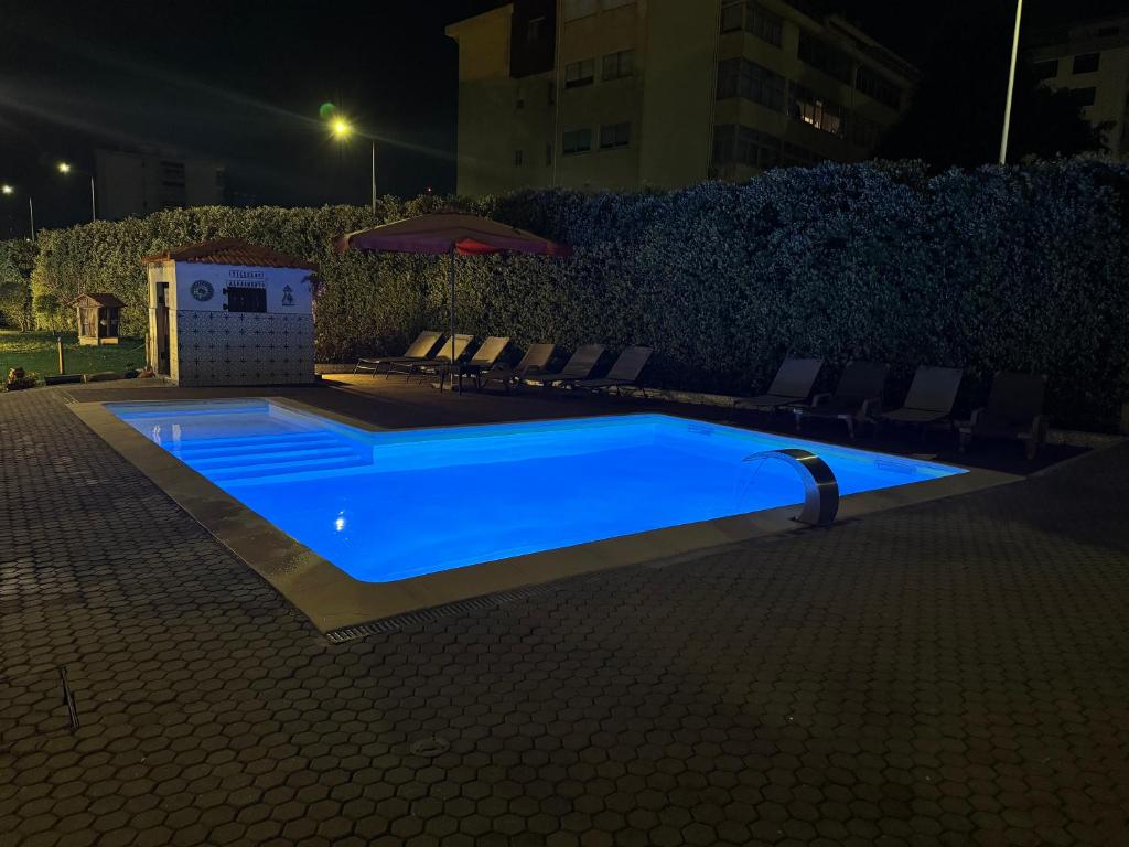 a blue swimming pool with chairs and an umbrella at VilleLay Alojamento VNG in Vila Nova de Gaia