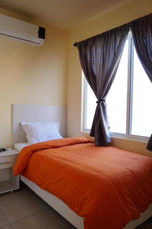 1 dormitorio con 1 cama con manta naranja y ventana en MV Suites en Monterrey