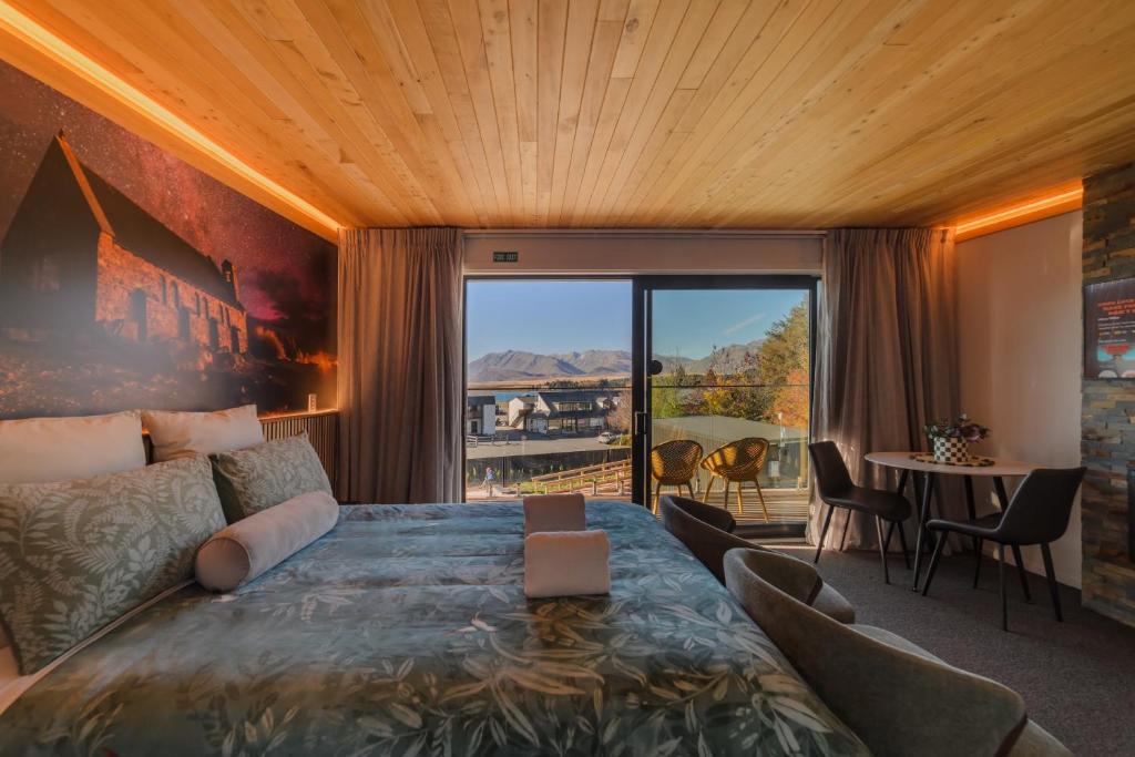 a bedroom with a large bed and a table with chairs at Starlight Escape - Ohana in Lake Tekapo