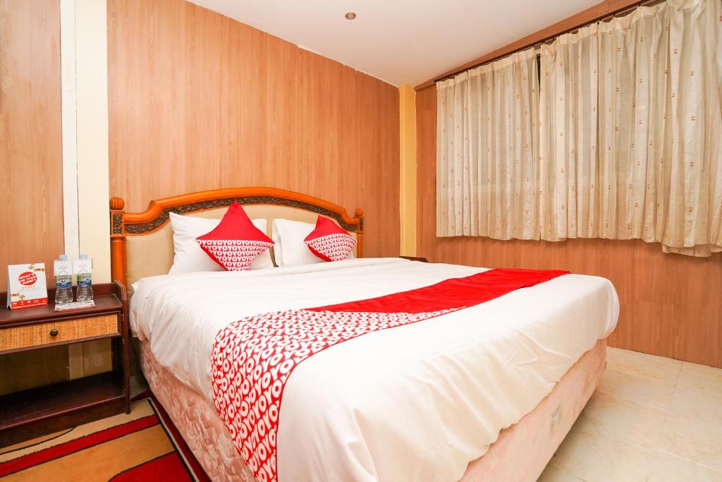 a bedroom with a large bed with red and white pillows at Super OYO Naomi Heritage in Surabaya