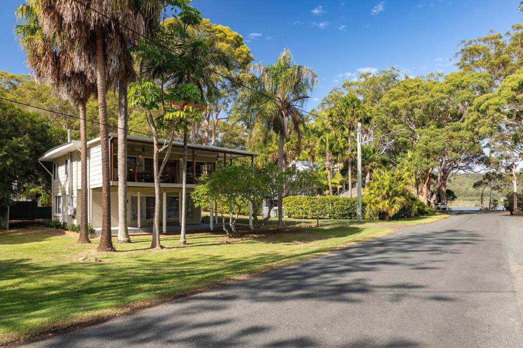 a house with palm trees on the side of a road at Amaroo Cottage Smiths Lake in Smiths Lake