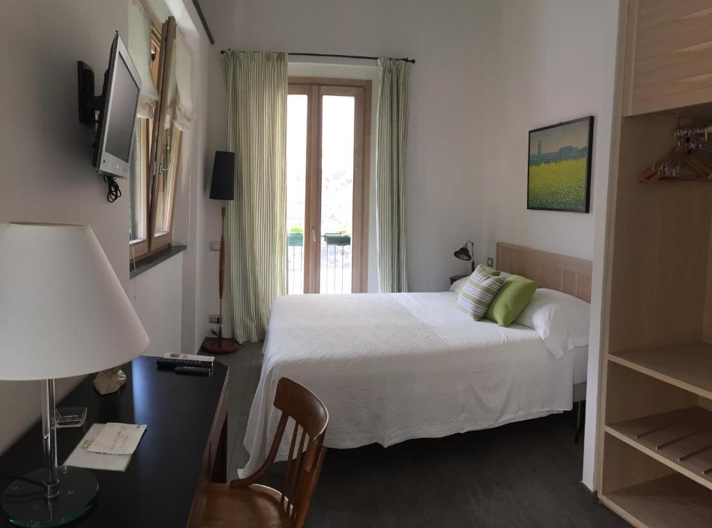 1 dormitorio con cama, escritorio y ventana en La Casa di Andrea Relais en Monterosso al Mare