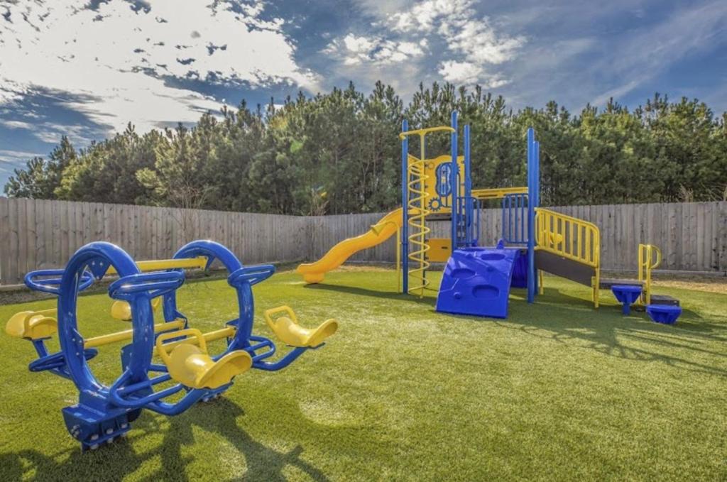 a playground with yellow and blue equipment in a yard at Humble cozy home in Humble