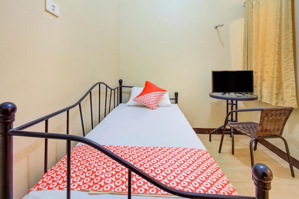 a bedroom with a bed with a red pillow and a chair at Hotel O Sofia Homestay Syariah in Bogor