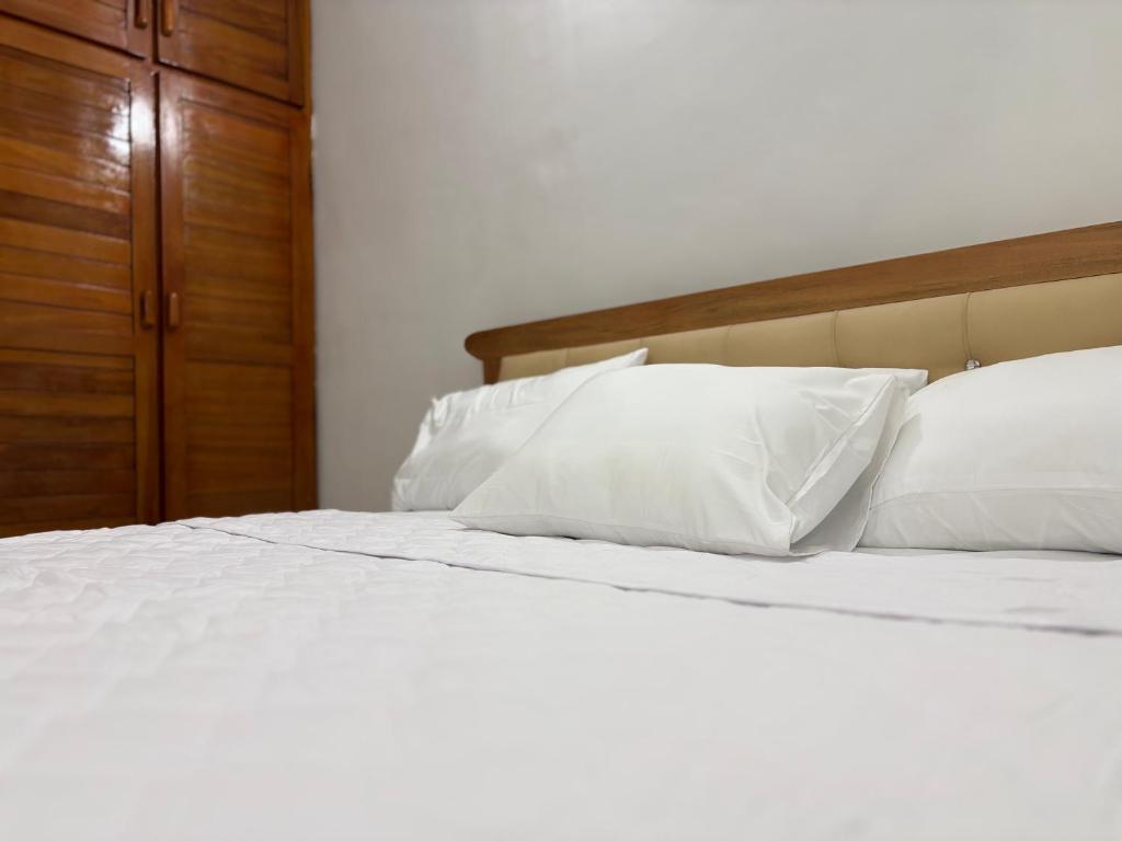 a white bed with white pillows and a wooden headboard at Luxury résidence Bassam in Moosou