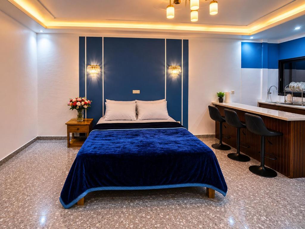 a bedroom with a blue bed and a kitchen at Résidence Tango - Appartements Meublés - 4 types in Bafoussam