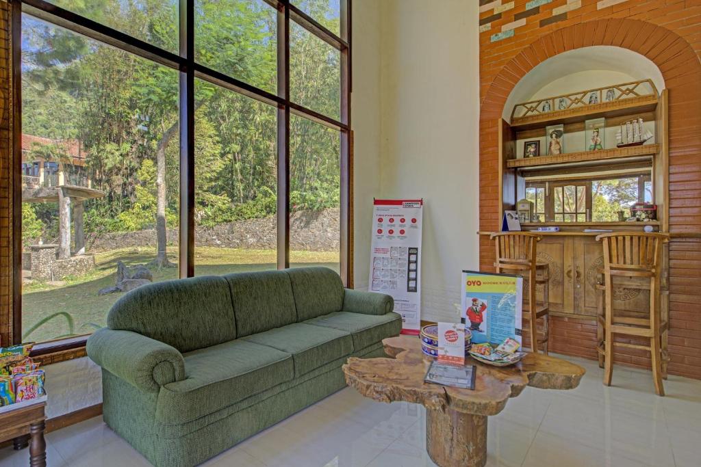 a living room with a green couch and a table at Hotel O Villa Inn App Trawas Bintaro Syariah in Kemloko-gede