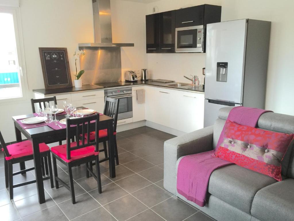 a kitchen and dining room with a table and a couch at Appartement Copenhague Disneyland in Montévrain