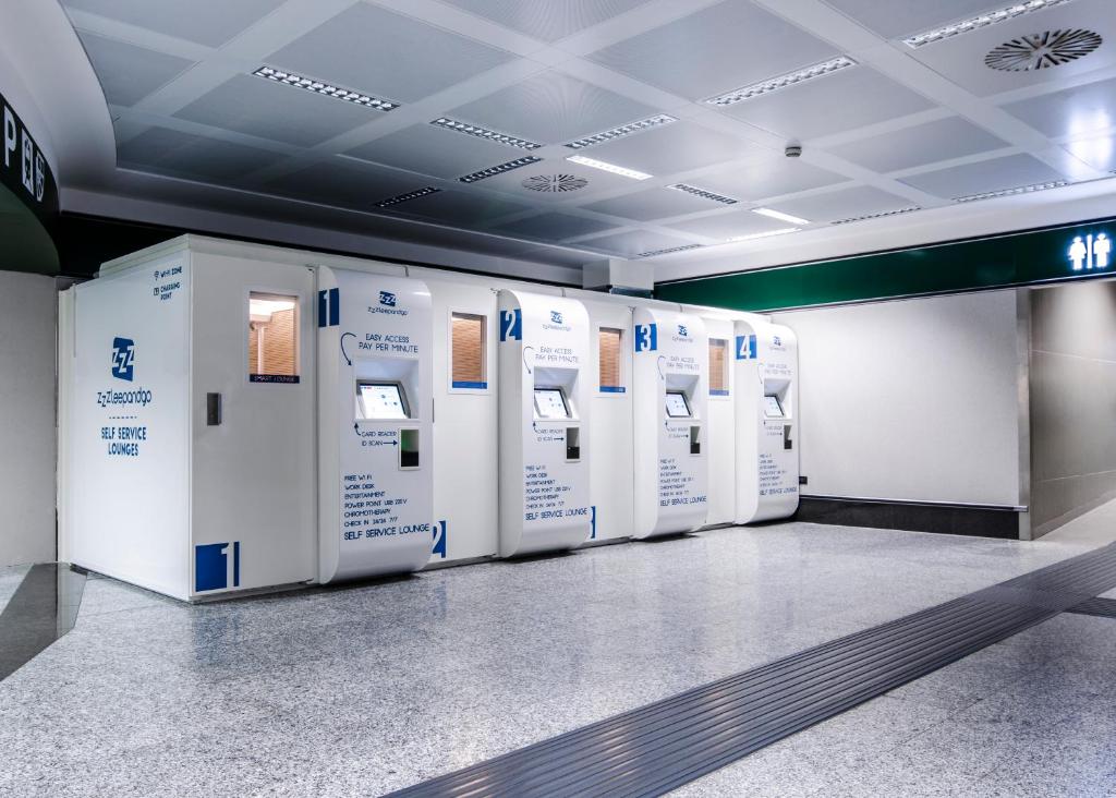 una fila di frigoriferi allineati in una stanza di Resting Pods - -ZZZleepandGo MXP Airport a Ferno