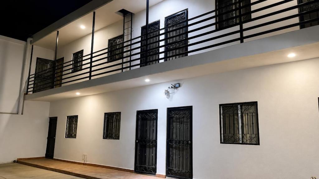 a white wall with black doors and a balcony at Lumina loft express minutes to consulate in Hermosillo