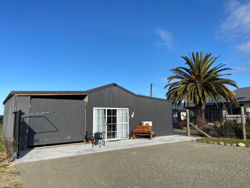 a black building with a palm tree in front of it at The Jam Shed in Waimate