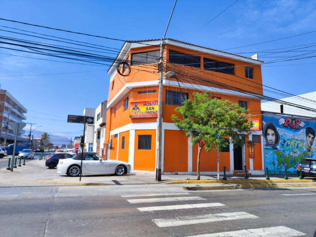 an orange building with a car parked in front of it at Hostal San Lorenzo in Iquique