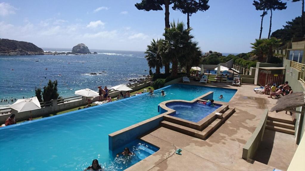 a large swimming pool next to a body of water at Algarrobo, Pinares de Canelillo in Algarrobo