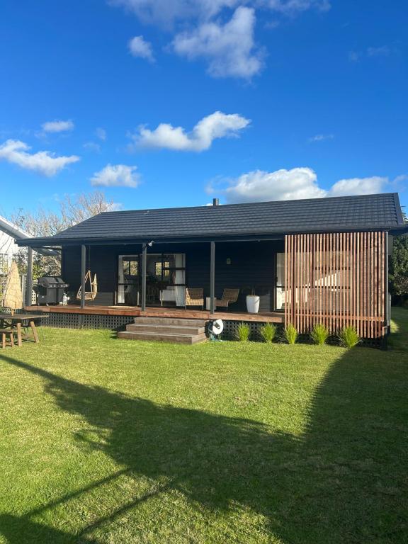 a house with a large lawn in front of it at Coastal Escape - Cooks Beach in Cooks Beach