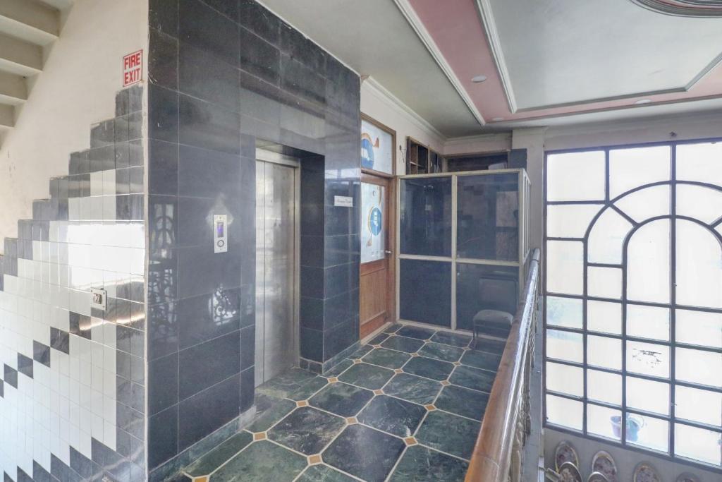 a bathroom with a walk in shower and a tile floor at Hotel O Mukut Mahal in Meerut