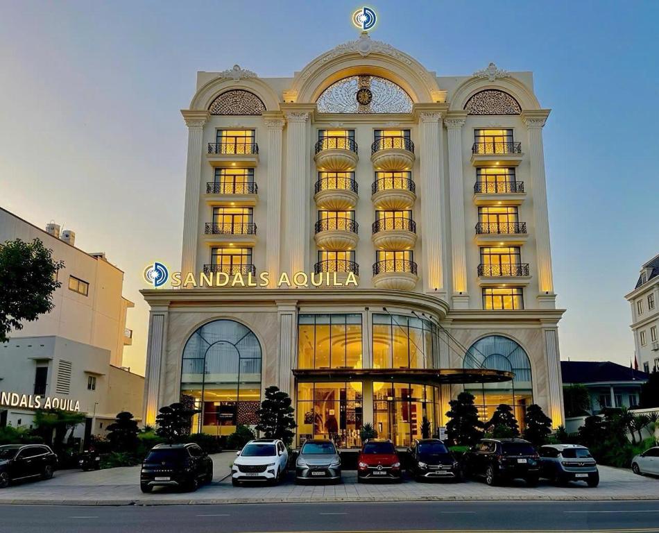 a large building with cars parked in front of it at SANDALS AQUILA HOTEL in Bảo Lộc