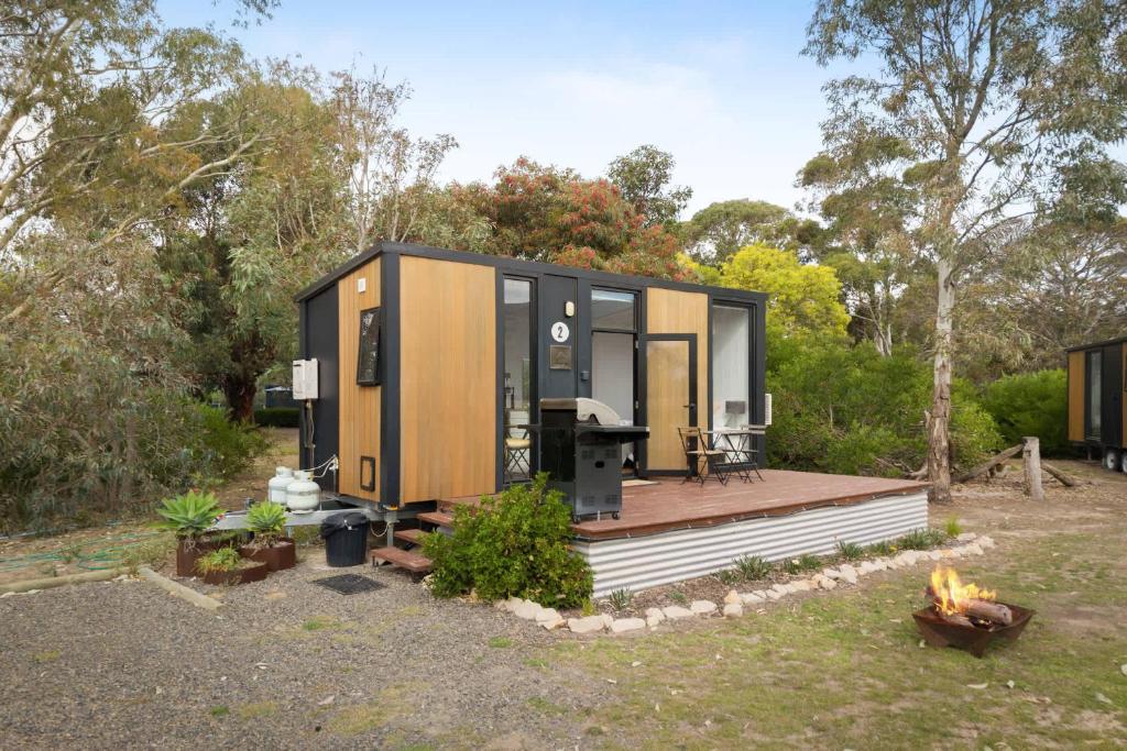 a tiny house with a deck and a fireplace at Halls Haven Tiny House 1 by Tiny Away in Halls Gap