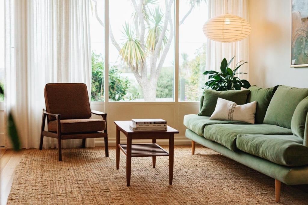 a living room with a green couch and a chair at Georgie Bay St Helens in St Helens