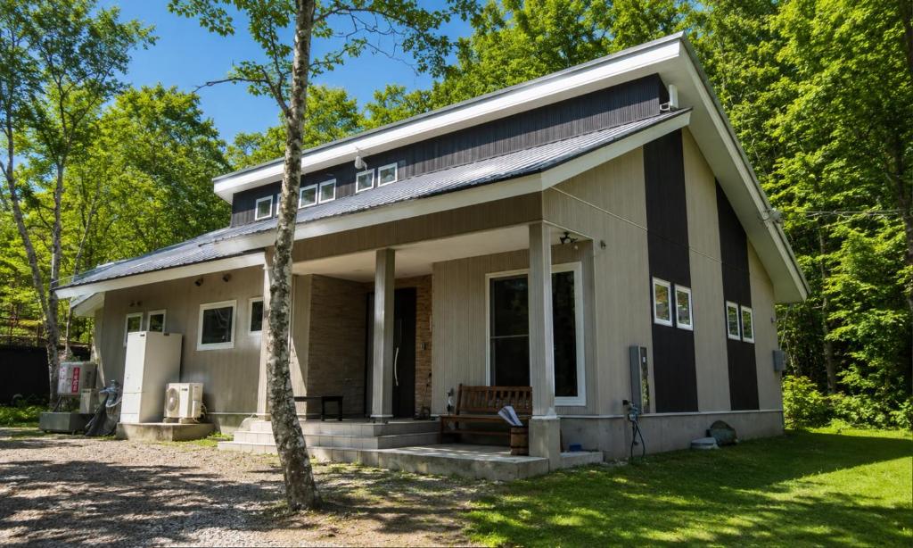 a house with a tree in front of it at Avanti Chalet Hakuba in Hakuba