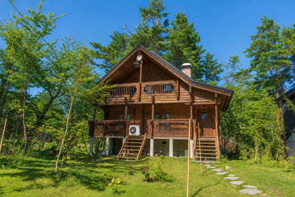 a log cabin in the woods with a deck at Le Mistral Hakuba in Hakuba