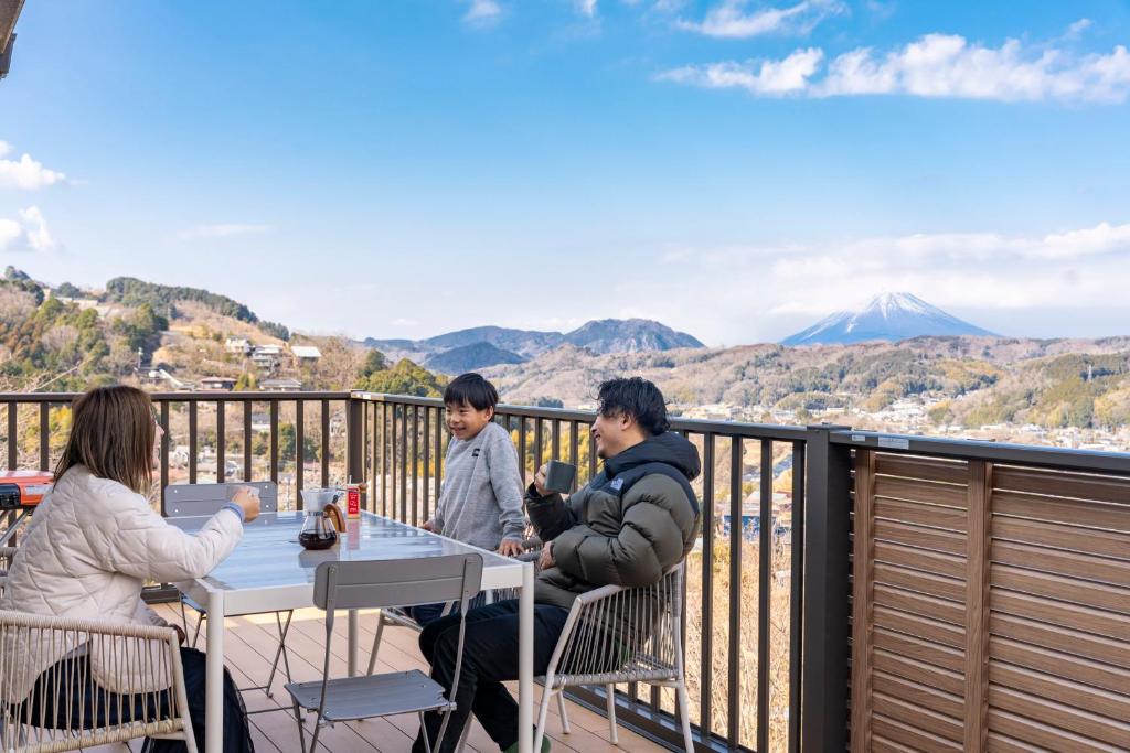 a group of people sitting at a table on a balcony at 天然温泉-富士山パノラマビュー-プライベートデッキで非日常体験を-伊豆の温泉付き貸別荘-中伊豆noie in Izu